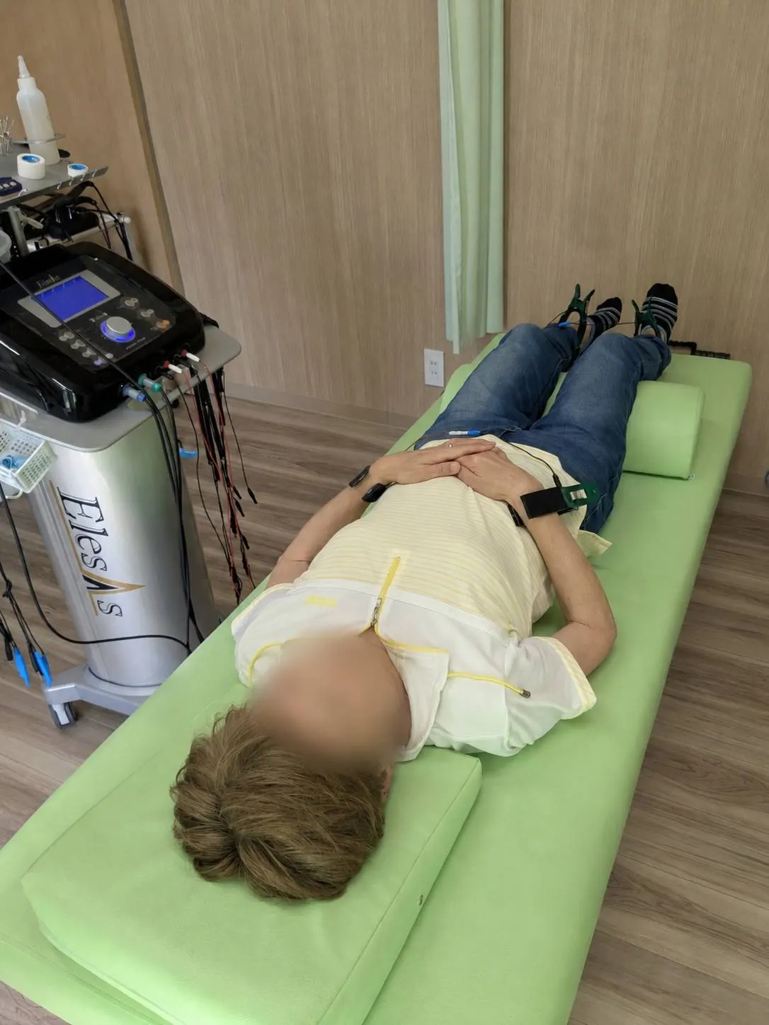 施術ベッドにうつ伏せになった状態で電極を装着し、エレサスによる全身通電施術を受けている様子