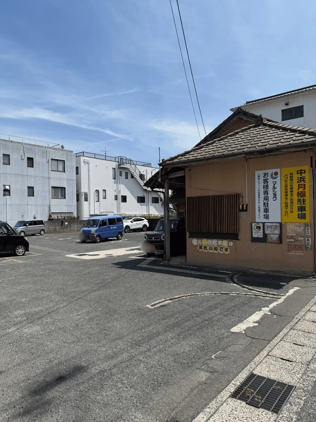 駐車場入口付近。右手の茶色い建物に「中浜月極駐車場」「マルショク お客様専用駐車場」の看板が掲示されている。
