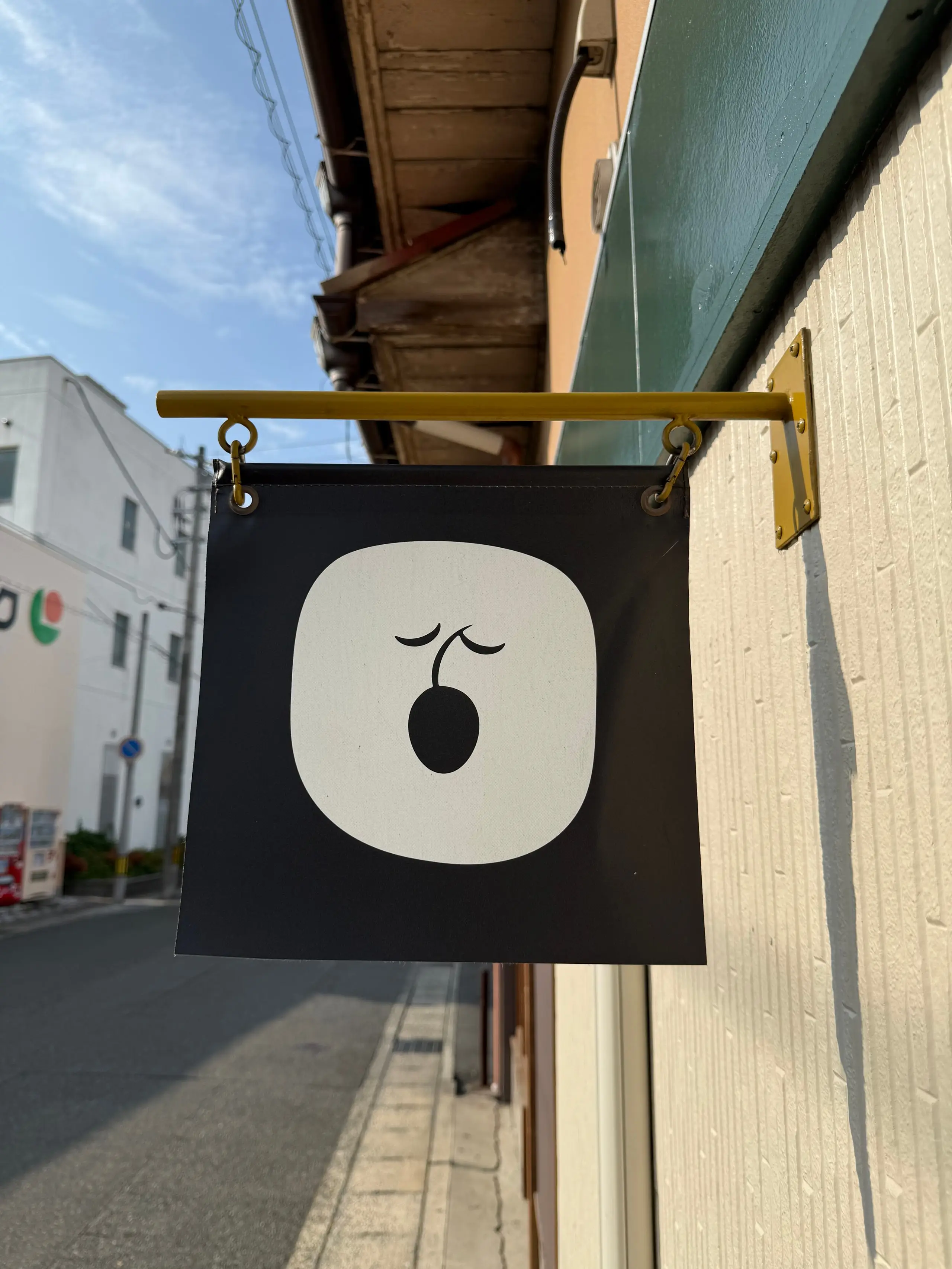 軒先に取り付けられた、オリーブのロゴが入った黒い袖看板。